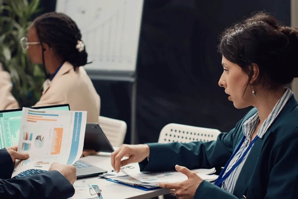 A businesswoman in a meeting reviews financial graphs and charts with a colleague.