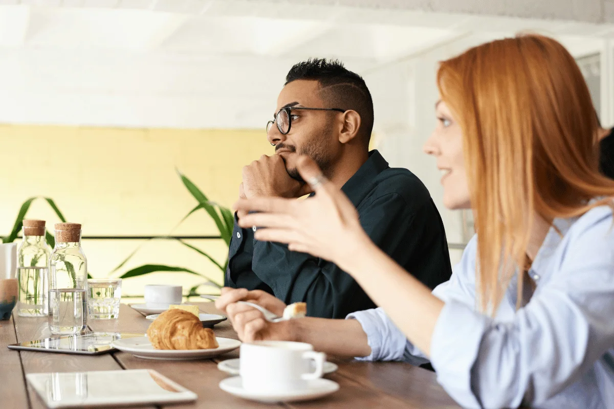 Colleagues discussing ideas over coffee at a café meeting.