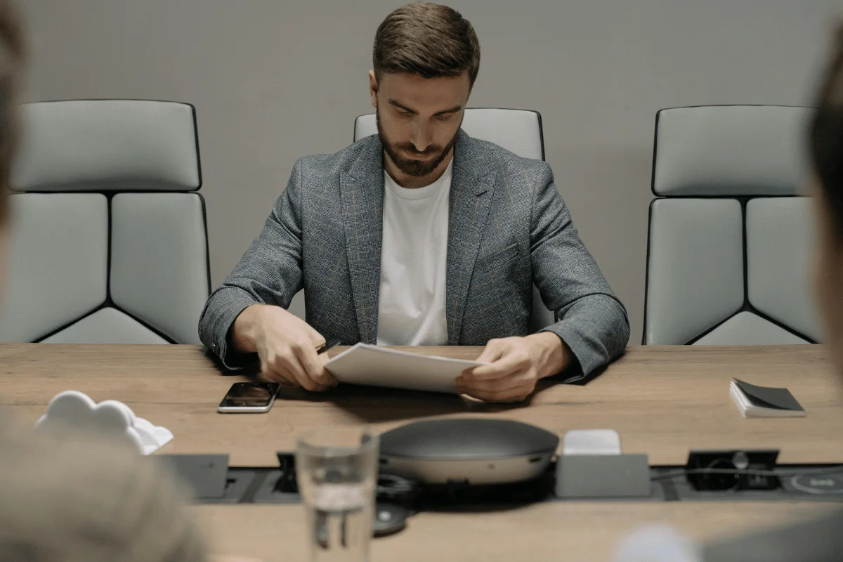 Business professional reviewing printed documents during a formal meeting at a conference table.