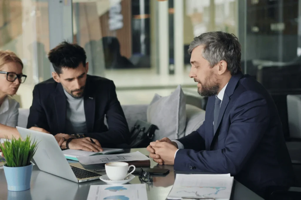 Three people in a modern office, engaged in a serious discussion.