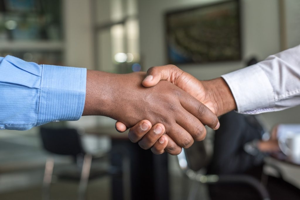 Two business professionals shaking hands after completing a digital marketing agency sale